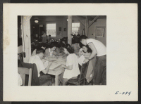 [recto] The evacuees grouped around this table are part of the Welfare Department. ;  Photographer: Parker, Tom ;  Denson, Arkansas.