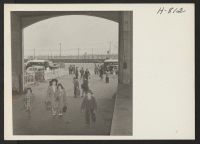 [recto] Passengers, for the Shawnee, Army Troop Transport, detailed to return 1100 persons of Japanese ancestry to their former homes in Hawaii, coming through the arches of the pier at Los Angeles Harbor. ;  Photographer: Mace, Charles E. ;  Los Angeles, Cal
