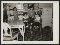 [recto] It's suppertime for the kiddies and in their well-furnished, well-stocked kitchen Mrs. George Isoda, left, and Mrs. Masumi Kaneko, right, ...