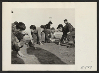 [recto] Grade school boys playing touch football during the recess play period. ;  Photographer: Parker, Tom ;  Amache, Colorado.