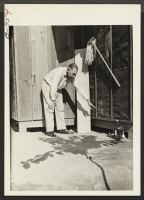 [recto] William Hoffman, Chief of the Fire Protection Section of WRA, pointing to burned tar paper on the side of Barracks ...