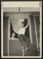 [recto] Manzanar, Calif.--Hanging out curtains in their barrack apartment at this War Relocation Authority center for evacuees of Japanese ancestry. ;  Photographer: Albers, Clem ;  Manzanar, California.