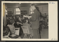[recto] Lieutenant Eugene Bogard explains the method of registration of Japanese and Japanese-Americans to a group of appointed personnel at the Manzanar Center. All evacuees between the ages of 18 and 38 were compelled to register. ;  Photographer: Stewart, Fr