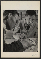 [recto] A woodcarving demonstrated by M. Y. Murakami, left, a student, and Y. Suzuki, right, the inspector, at the Arts and Crafts Festival, which was sponsored by the Education Division and the Pioneer, the center newspaper. ;  Photographer: Coffey, Pat ;  A