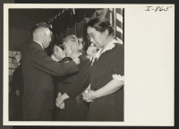 [recto] Gold stars are here being presented by K. Okura, USO representative, to mothers whose sons were killed in action. This presentation was made in the high school auditorium April 21, 1945. ;  Photographer: Iwasaki, Hikaru ;  Amache, Colorado.