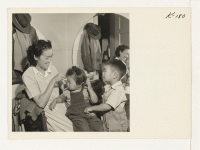 [recto] Mrs. George Fujita, Route 1, Box 112, Petaluma, California, is shown combing her daughter Judy's hair. Bobby, her son, looks on. They were former residents of the Granada Relocation Center. ;  Photographer: Iwasaki, Hikaru ;  Petaluma, California.