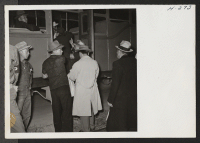 [recto] New arrivals at Topaz, trip 14, from Tule Lake, are shown being helped to an awaiting bus by one of the wardens. ;  Photographer: Mace, Charles E. ;  Topaz, Utah.