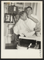 [recto] Kyuji Hozaki at work in his barber shop, 822 E. 7th St., Los Angeles, recently reopened it after leaving Rohwer. ...