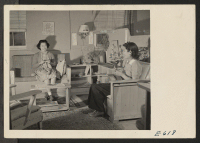 [recto] Mrs. S. Nako entertains a friend, Mrs. William Hosokawa, for an afternoon's knitting. Starting with a bare barracks room, some scrap and some mail order lumber and much ingenuity, S. Nako, a young Nisei, constructed the typically modern furniture shown.