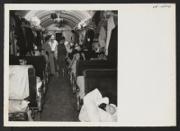[recto] A scene in one of the twenty coaches on trip 15, Topaz to Tule Lake. The train monitor is seen conferring with a car captain and some of the passengers regarding the comfort of the latter. ;  Photographer: Mace, Charles E. ; , .