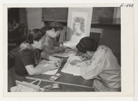 [recto] Three students of an adult crafts class doing steamed crayon work in making table cloths and wall hangings. ;  Photographer: Parker, Tom ;  Amache, Colorado.