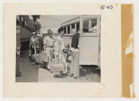 [recto] First evacuees to arrive at the Granada railroad station boarding buses to be transported to the relocation center. These evacuees hail from Merced Assembly Center, Merced, Calif. ;  Photographer: Parker, Tom ;  Amache, Colorado.