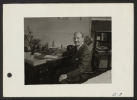 [recto] Charles F. Ernst, Project Director, at his desk in the Administration building at the Topaz Relocation Center. ;  Photographer: Parker, Tom ;  Topaz, Utah.