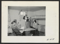 [recto] The Ninomiya family in their barracks room at the Amache Center. The mother's handiwork is preparing drapes, fashionable furniture out ...