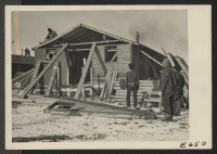 [recto] Workmen reconstructing an abandoned CCC building which was moved to the center from a nearby CCC camp. The building will be used to augment a resident barracks being used for a primary school. ;  Photographer: Parker, Tom ;  Heart Mountain, Wyoming.