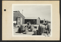 [recto] Poston, Ariz.--Tom Nishemarv [Nishimura?] and Tom Enomoto inspecting tractors which have been received at this War Relocation Authority center for evacuees of Japanese ancestry. ;  Photographer: Clark, Fred ;  Poston, Arizona.