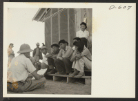 [recto] Norris James, War Relocation Authority representative, gives instructions and assignments to the newspaper staff of evacuees of Japanese ancestry at this center where they are spending the duration. ;  Photographer: Stewart, Francis ;  Poston, Arizona
