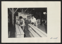 [recto] Two young Nisei evacuees wood workers constructing benches for the grade and high school at this relocation center. ;  Photographer: Parker, Tom ;  Heart Mountain, Wyoming.