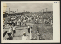 [recto] Closing of the Jerome Center, Denson, Arkansas. Residents remaining in the Jerome Center awaiting transportation to other localities crowd the streets as they return to their homes after the departure of a train. ;  Photographer: Mace, Charles E. ;  D