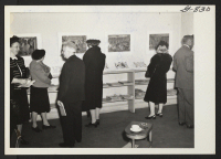 [recto] Spectators are viewing paintings and drawings of relocation center life by Miss Mine Okubo, Nisei, who resettled to new York ...