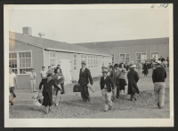[recto] A family group of Tuleans being shown to their new living quarters. ;  Photographer: McClelland, Joe ;  Amache, Colorado.