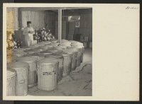 [recto] Closing of the Jerome Center, Denson, Arkansas. Dishes from the center's thirty-three mess halls were carefully packed in straw and put in G.I. cans ready for shipment. Angelo Girardo of the Denver Office is shown supervising the work. ;  Photographer: