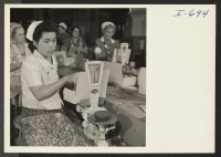 [recto] Mrs. Asano Hashiba, formerly of the Rohwer Relocation Center, is checking the weight of lima beans on the package line ...
