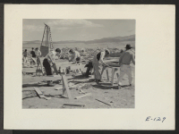 [recto] Salvaging lumber from the scrap pile, these evacuee residents are preparing lumber for use in making small items of resident furniture. ;  Photographer: Parker, Tom ;  Heart Mountain, Wyoming.