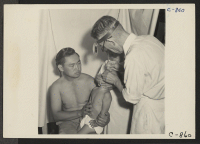 [recto] Manzanar, Calif.--Dr. Takahashi, Eye, Ear, Nose and Throat Specialist, lances sty on very young patient in the medical clinic at this War Relocation Authority center for evacuees of Japanese ancestry. ;  Photographer: Lange, Dorothea ;  Manzanar, Cali