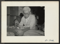 [recto] An evacuee of Japanese ancestry contemplates a move in the age-old Japanese game of Go. ;  Photographer: Stewart, Francis ;  Rivers, Arizona.