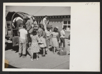 [recto] New arrivals from the Jerome Center, having passed through the induction routine, are shown boarding trucks which will take them to a mess hall and later to their new quarters. ;  Photographer: Mace, Charles E. ;  Newell, California.