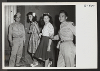 [recto] Between dances at the Washington USO for Nisei servicemen and their guests, several boys from Hawaii and their partners, USO hostess Sophie Ravetta, and a guest, Tess Amitrano, chat outside the USO. ;  Photographer: Van Tassel, Gretchen ;  Washington