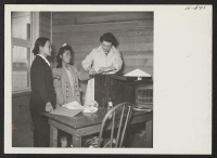 [recto] A scene in the induction center at Tule Lake, where a mother and daughter are having impressions made of their finger prints upon arrival at Tule Lake from the Topaz Center. ;  Photographer: Mace, Charles E. ; , .