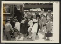 [recto] This group arrived by train from Elk Grove, California, and are boarding a bus for Manzanar, a War Relocation Authority center where evacuees of Japanese ancestry will spend the duration. ;  Photographer: Stewart, Francis ;  Manzanar, California.