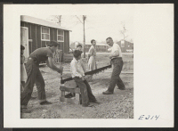 [recto] Residents of this center are cutting plaques from a green oak log for an oil painting. ;  Photographer: Parker, Tom ;  McGehee, Arkansas.