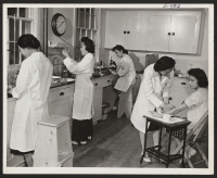 [recto] Four technicians and a patient in the hospital laboratory. A blood test patient. ;  Photographer: Parker, Tom ;  Amache, Colorado.