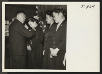 [recto] Gold stars are here being presented by K. Okura, USO representative, to mothers whose sons were killed in action. This presentation was made in the high school auditorium April 21, 1945. ;  Photographer: Iwasaki, Hikaru ;  Amache, Colorado.