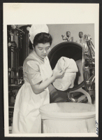 [recto] Michiye Fujimoto, formerly of Del Rey, California, and Gila River Center, removes linens from the sterilizer at the Kansas City ...
