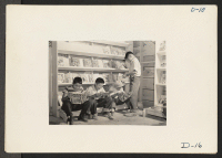 [recto] Tule Lake, Newell, Calif.--Four little evacuees from Sacramento, California, read comic books in the newsstand at this War Relocation Authority center for evacuees of Japanese descent. ;  Photographer: Stewart, Francis ;  Newell, California.
