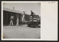 [recto] While the new arrivals were being fed at the mess hall, their luggage was delivered to their newly assigned barracks to be on hand when they arrived. ;  Photographer: Mace, Charles E. ;  Newell, California.