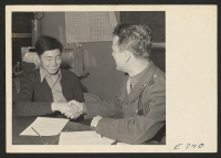 [recto] Mitsuma Yakahari, 21-year-old Japanese-American and former resident of Red Bluff, California, shakes hands with Sergeant Robert I. Bischoff, a member ...