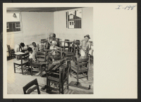[recto] Closing of the Jerome Center, Denson, Arkansas. A recruited crew of Jerome evacuees remove the arms from the high school classroom desks prior to crating them and shipping them to other centers. ;  Photographer: Iwasaki, Hikaru ;  Denson, Arkansas.