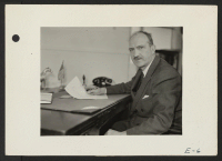 [recto] Charles F. Ernst, Project Director, at his desk in the Administration building at the Topaz Relocation Center. ;  Photographer: Parker, Tom ;  Topaz, Utah.