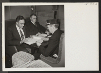 [recto] Roscoe Bell, representing W.R.A. on trip 15, Topaz to Tule Lake, is shown in conference with Southern Pacific representative William ...