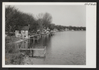 [recto] Strung along the Des Plaines River at McHenry, Illinois, are several small cottages and small docks from which row boats ...