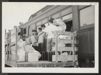 [recto] INCOMING--Unloading hand baggage from coaches. ;  Photographer: Aoyama, Bud ;  Heart Mountain, Wyoming.