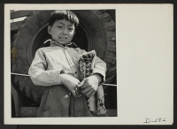 [recto] Manzanar, Calif.--A small boy of Japanese descent at Memorial Day services. Evacuee Boy Scouts took a leading part in the ceremony held at this War Relocation Authority center. ;  Photographer: Stewart, Francis ;  Manzanar, California.