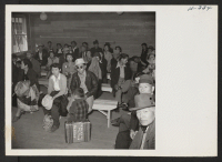[recto] New arrivals from Topaz wait in the induction center at Tule Lake while their baggage is being inspected. This was the first step in the induction routine. ;  Photographer: Mace, Charles E. ; , .