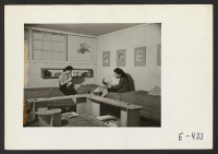 [recto] Sunday afternoon and the three girls who occupy this barracks room relax. The furniture, the book niches, flower pot and print mats are all made by the girls from scrap lumber and scrap pieces of wall board. ;  Photographer: Parker, Tom ;  Amache, Col