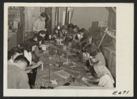 [recto] A class of early teen age students of Japanese ancestry, in a craft shop at the Heart Mountain Relocation Center. Under trained supervisors, students learn to make art objects of wood and paper. ;  Photographer: Parker, Tom ;  Heart Mountain, Wyoming.